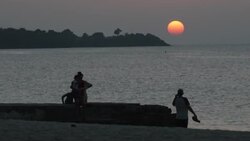 Beach, palm trees, sunset and people in a boat in Grenada News Clip