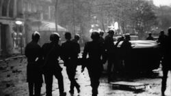 B&W Riot policemen throwing hand grenades with tear gas on street, rear view, Europe Stock Footage