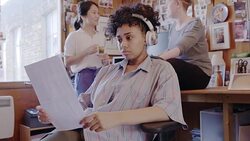 Creative businesswoman reading paperwork and listening to music with headphones in office Stock Footage