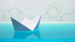 Paper boat floating in bath, happy sunny future on horizon, dreams, macro shot Stock Footage