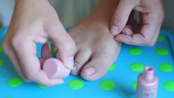 girl paints nails on her right foot Stock Footage