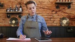 Barber using digital tablet while writing receipt Stock Footage