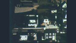 1960s: View of town zooms in on white two-story house in quiet neighborhood Stock Footage