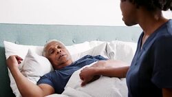 Healthcare worker visiting senior man suffering with depression lying in bed - shot in slow motion Stock Footage