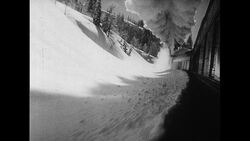 California, 1952: A train has difficulty going uphill on a snowy mountain even though it is preceded by a snow plower Stock Footage