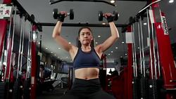 Young Asian muscular woman exercising dumbbell shoulder press in the gym, lifestyle sport and bodybuilding concept Stock Footage