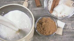Slow motion in a mug pour milk near the ingredients for cocoa Stock Footage