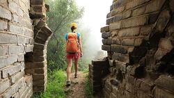 Woman hiker hiking on the unrestored great wall Stock Footage