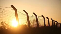 The sun is sinking behind the fence Stock Footage