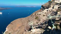 Gondola going up mountain in Fira, Thira overlooking the Caldera volcanic Aegean Sea with greek Orthodox cross in Santorini Greece Stock Footage