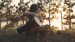 Beautiful young hippie woman with dreadlocks playing on djembe. Funky woman drumming in nature on an ethnic drum at sunset or sunrise with a human skull Stock Footage