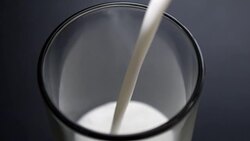 Pouring a glass of milk on black background Stock Footage