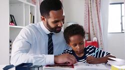 Businessman father sitting at desk in sons bedroom helping him with homework Stock Footage