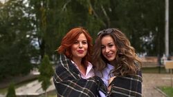 SLOW MOTION: Two young women cute communicate with each other. The weather is cold, so women hide behind a plaid. Women smile when communicating. Stock Footage