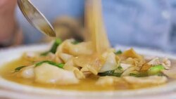 close up woman eating hot thai fried noodle with pork and broccoli with spoon and fork. Stock Footage