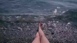 View of sexy female legs on a pebble beach while woman is sunbathing Stock Footage