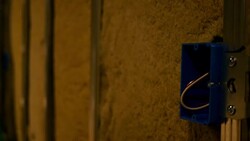 Camera pans across unfinished basement to uncovered electrical box Stock Footage