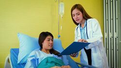 Young Asian female doctor and woman patient lying in bed while discussing and consultation medical examination at hospital room , Healthcare and medical concept, Doctor and patient Stock Footage