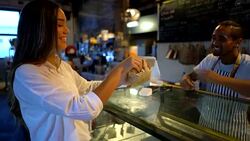 Beautiful woman at a bakery receiving her food for take out with a coffee to go from the friendly salesman Stock Footage