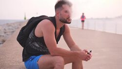 Handsome man sitting by the water and vaping cigarette Stock Footage