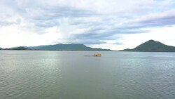 Aerial shoot bamboo raft house floating in lake with mountain and sky background Stock Footage