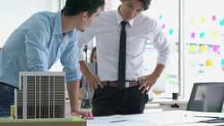 Architects male and Businessman are paper blueprint and building model. Business man suggest idea to designer at modern office. concept of construction, architecture, development and creative. Stock Footage