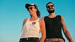 young woman and man enjoying the sunset in front of a blue sky Stock Footage