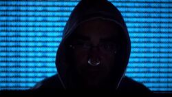 Hooded hacker coding security data on a computer in dark room Stock Footage