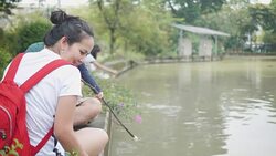 Asian young mother and young father with her adorable two year old girl playing outdoors with love, feeding food to fish and turtle. concept of family love of nature. happy children with the love of parents. Stock Footage