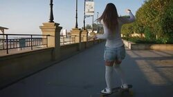 Young stylish attractive woman skateboarding at sunrise on seafront, slow motion Stock Footage