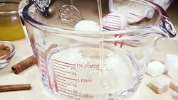 Slow motion glass measuring cup on the table near the ingredients Stock Footage