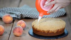 Cook decorating a cake with icing sugar with a piping bag. Summer peach pie with caramel sugar crumb Stock Footage