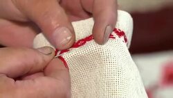 A woman is embroidering an ornament with a red thread. The process of decorating decorative towels embroidered red ornament. Stock Footage