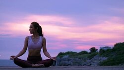 Happy young woman relaxing by practicing yoga on the beach at sunset, Sunrise background. Fitness, sport, yoga and healthy lifestyle concept. Stock Footage