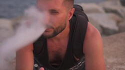 Handsome pensive bearded man vaping cigarette at beach Stock Footage