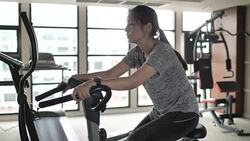 Asian Woman Exercise Cycling in Gym Stock Footage