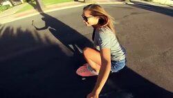Point of view of happy carefee girl skateboarding down street at sunset holding selfie camera Stock Footage
