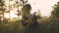 Beautiful young hippie woman with dreadlocks playing on djembe. Funky woman drumming in nature on an ethnic drum at sunset or sunrise Stock Footage