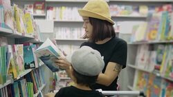 Young mother is choosing a book with her son. Stock Footage