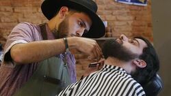 Barber trimming beard of customer in hair salon Stock Footage