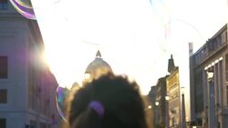 CLOSE UP: Big soap bubble flies by unrecognizable tourist watching the sunset. Stock Footage