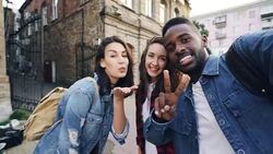 Point of view shot of attractive young men and women travelers taking selfie in the street posing and laughing holding camera. Modern technology and travelling concept. Stock Footage