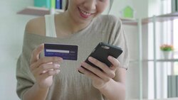 Attractive asian woman using credit card paying with mobile phone. Stock Footage