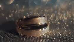 Wedding rings lying on shiny surface shining with light close up macro Stock Footage