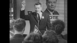 1960s: Man on stage talks into microphone, crowd cheers Stock Footage