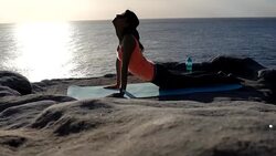 Young adult female practicing yoga next to a peaceful sea and a beautiful sunrise Stock Footage