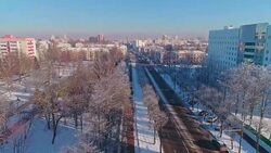 The aerial drone view along the street with the park, trees covered by frost, residential and office buildings with orbit camera motion. Stock Footage