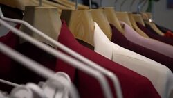 Dolly close up shot of many colors of fashionable business suits hanging on rack for sale in store Stock Footage