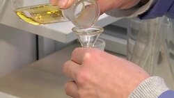 Laboratory glass beaker. The laboratory assistant pours a yellow liquid into the glass beaker. Experience in the laboratory. Stock Footage