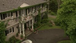 HIGH ANGLE DOWN OF TWO-STORY COLONIAL STYLE HOUSE OR SMALL MANSION. SEE WHITE PILLARS OR COLUMNS IN FRONT NEAR ENTRANCE TO DOORWAY AND WHITE RAILINGS OF BALCONY ON SECOND FLOOR. SEE SILVER CONVERTIBLE CAR PARKED IN DRIVEWAY. SEE GREEN GRASS OR LAWN AND TR Stock Footage